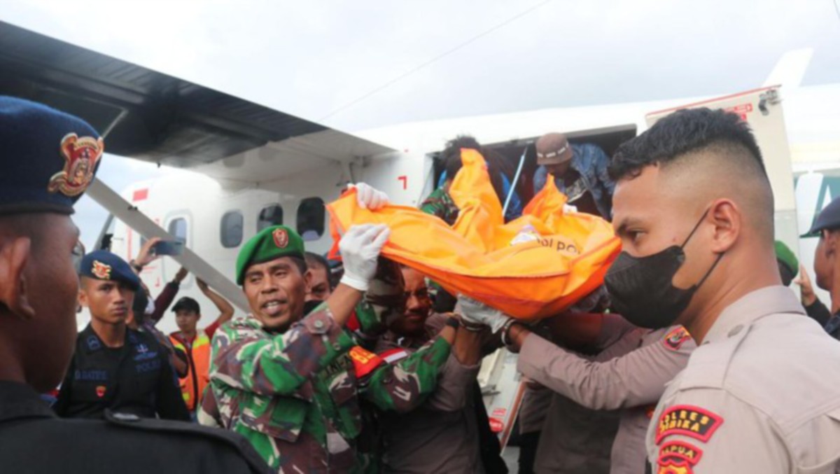 PASUKAN keselamatan membantu mengangkat mayat sebaik tiba di Timika. FOTO Agensi
