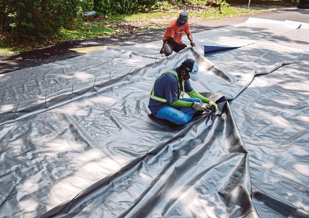 PEKERJA kontraktor giat mempersiapkan kanvas untuk menutup tanah runtuh bagi mengurangkan risiko runtuhan. FOTO Bernama
