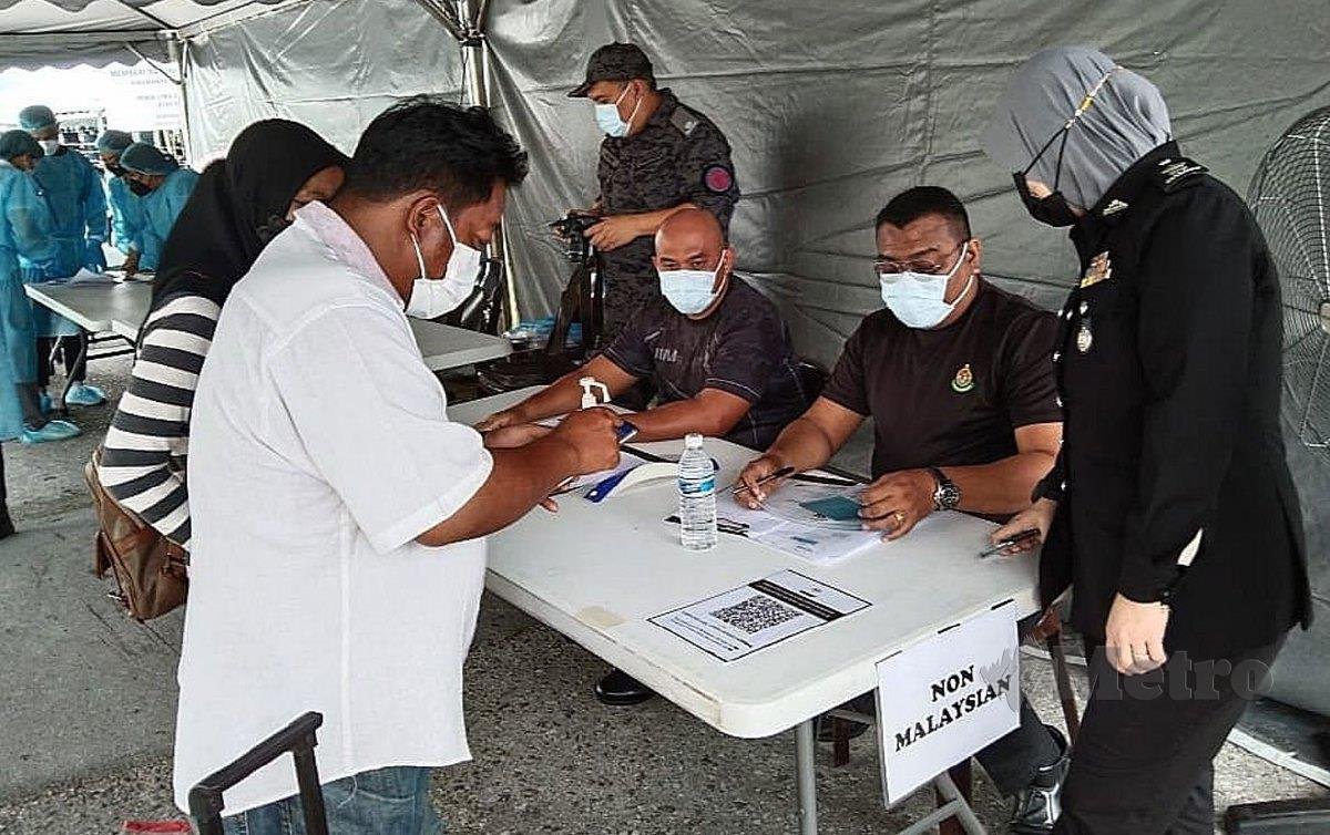PETUGAS keselamatan dan kesihatan memeriksa rakyat Indonesia yang mempunyai permit bekerja di Sarawak yang mahu memasuki negeri ini melalui ICQS Tebedu, hari ini. FOTO Mohd Roji Kawi