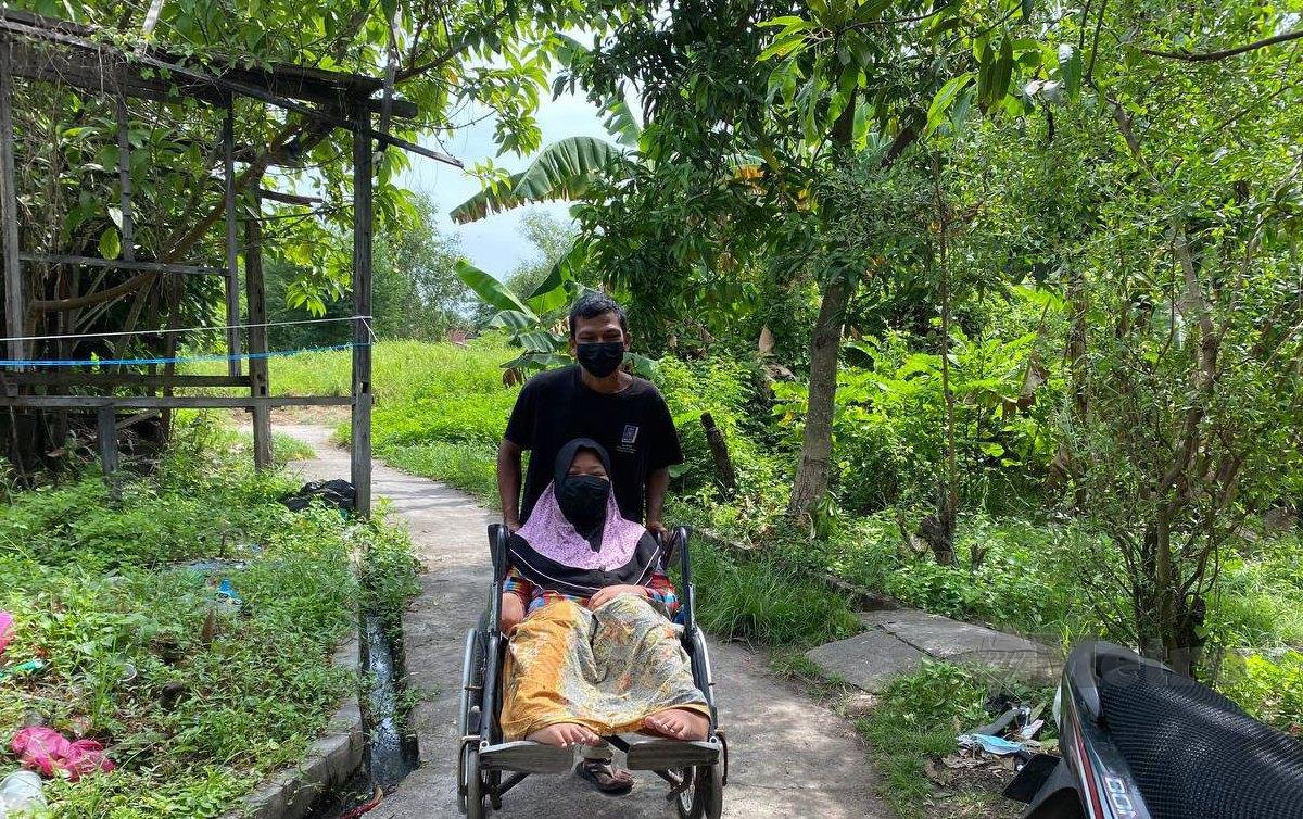 MOHD Sofi Osman,38, mengerah kudratnya untuk membawa isterinya,  dengan hanya menggunakan kerusi roda. FOTO Nur Izzati Mohamad