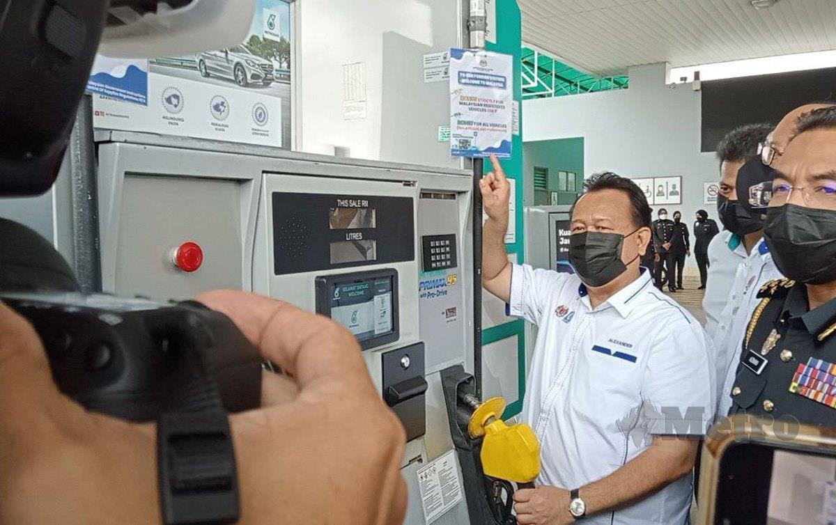 DATUK Seri Alexander Nanta Linggi menunjukkan poster Ron95 untuk kenderaan bernombor pendaftaran Malaysia dalam lawatannya di sebuah stesen minyak di Jalan Lingkaran Dalam di sini. FOTO Omar Ahmad