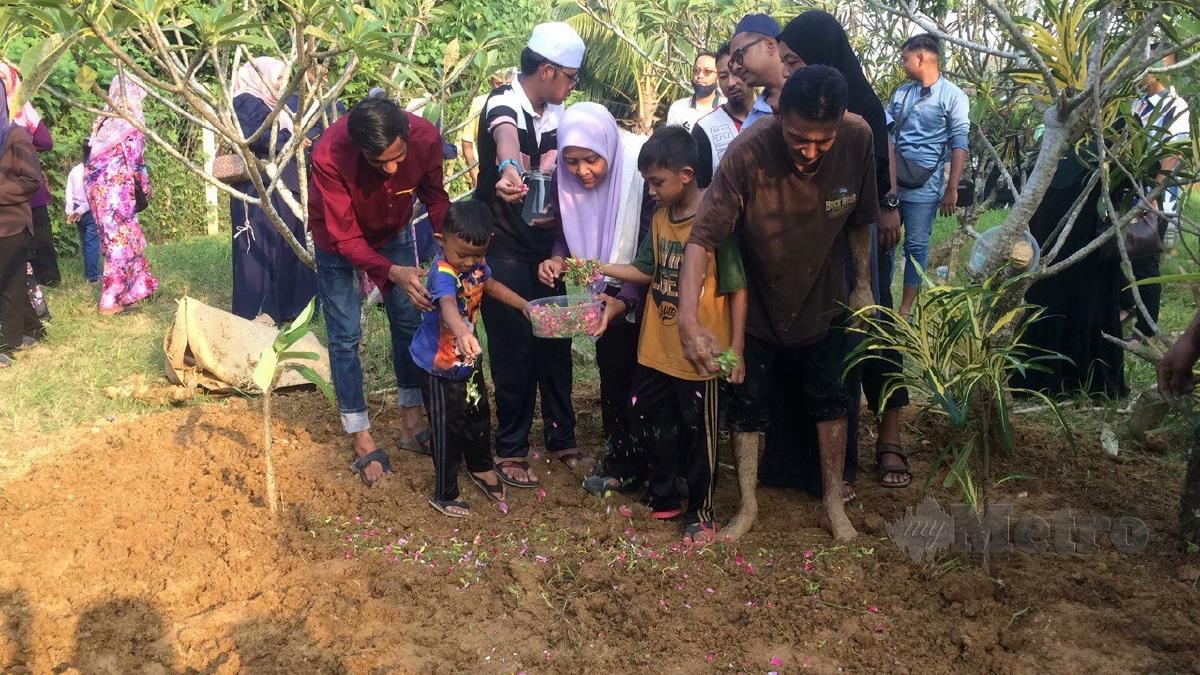 Kedua-dua anak jururawat Allahyarham Munirah menabur bunga mawar di pusara ibu mereka di Tanah Perkuburan Islam Haji Talib, Kampung Paya Tengah, Beseri, Padang Besar. FOTO AIZAT SHARIF