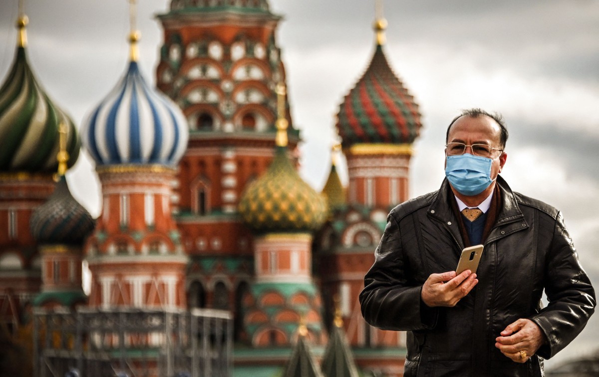 Seorang pelancong mengenakan pelitup muka berjalan berhampiran Red Square di Moscow. - FOTO AFP
