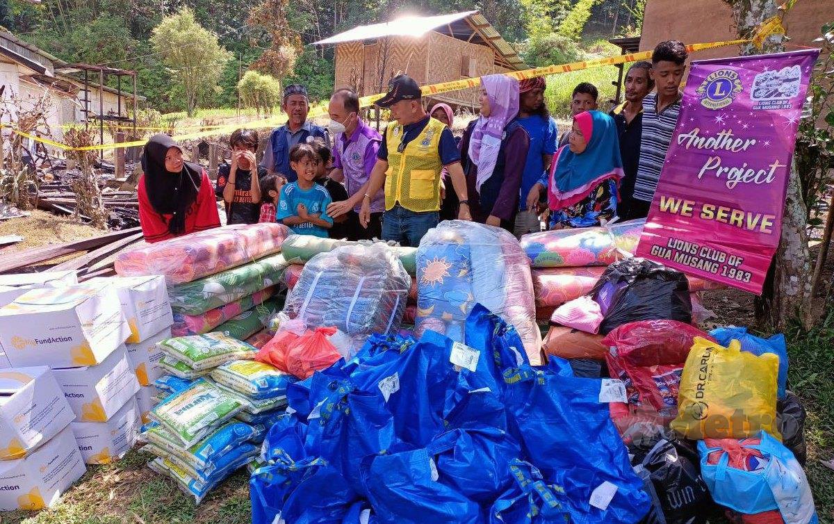 RAYMOND Ho (tengah) menyampaikan sumbangan kepada keluarga Lidya (kiri) di Kampung Galang, Pos Hau. FOTO Paya Linda Yahya