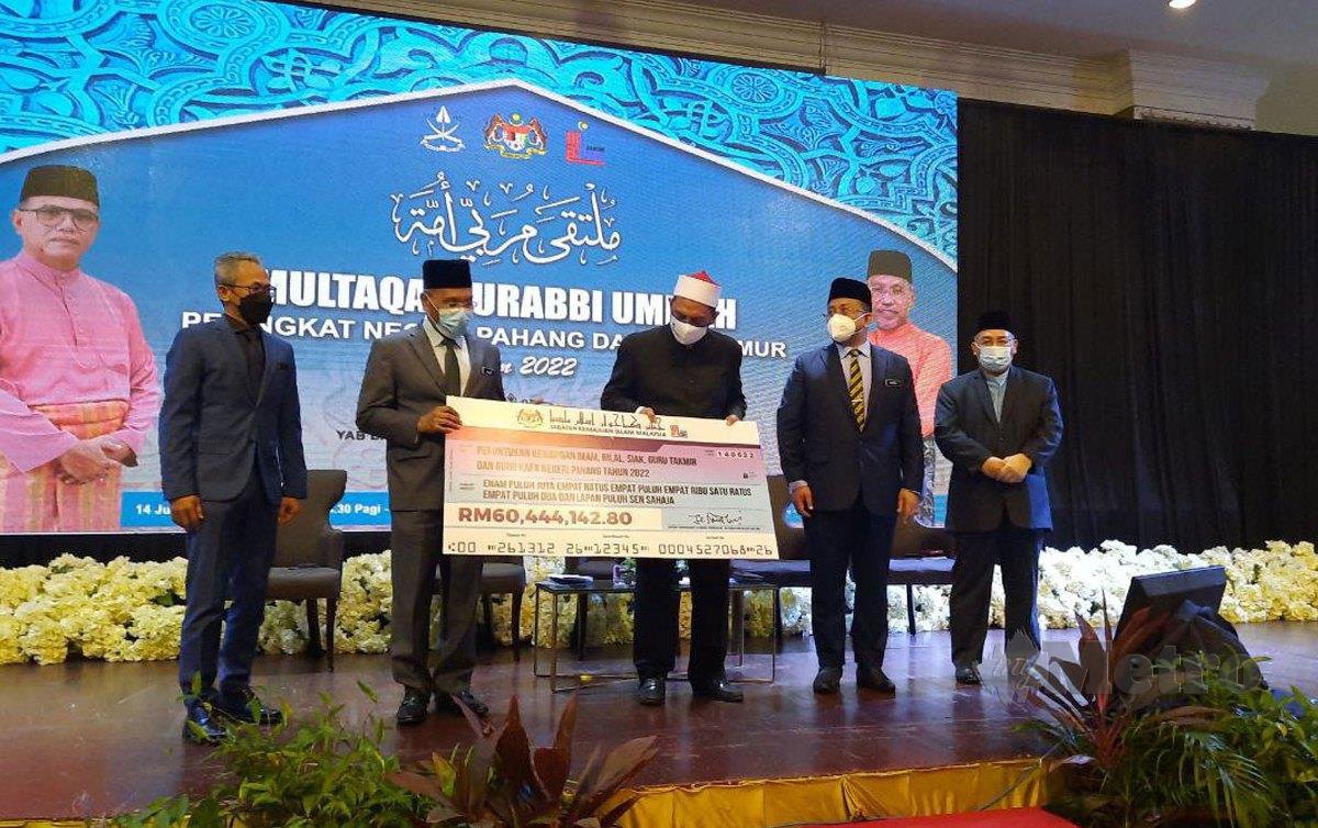 DATUK Idris Ahmad (dua dari kiri) menyampaikan replika cek kepada Datuk Seri Syed Ibrahim Syed Ahmad (tengah) sempena Multaqa Murabbi Ummah Peringkat Pahang di Kuantan. FOTO Asrol Awang