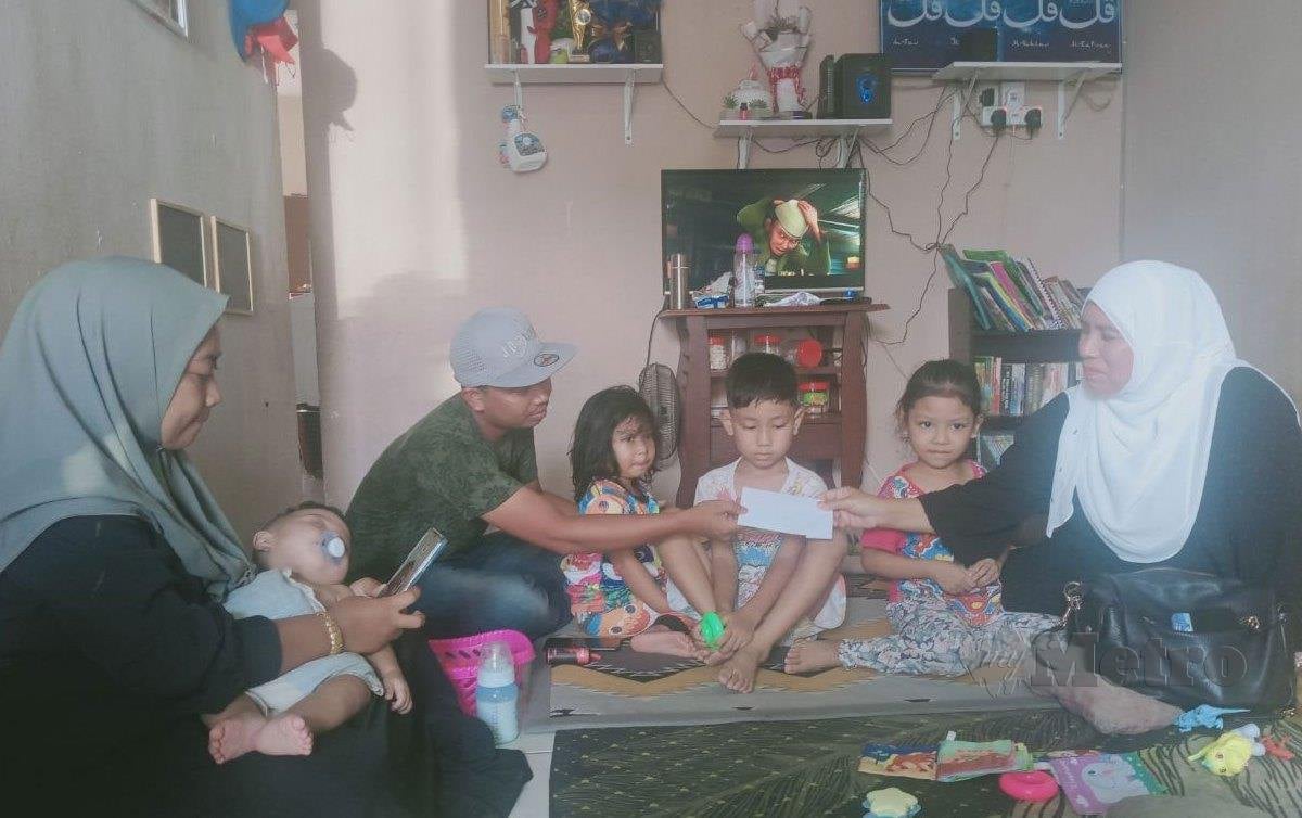 NORFADILAH Mansor (kanan) ketika menyampaikan sumbangan kepada Muhammad Rushdi bapa kepada lima anak berusia dari 9 bulan hingga 12 tahun, Seremban. FOTO Mohd Khidir Zakaria