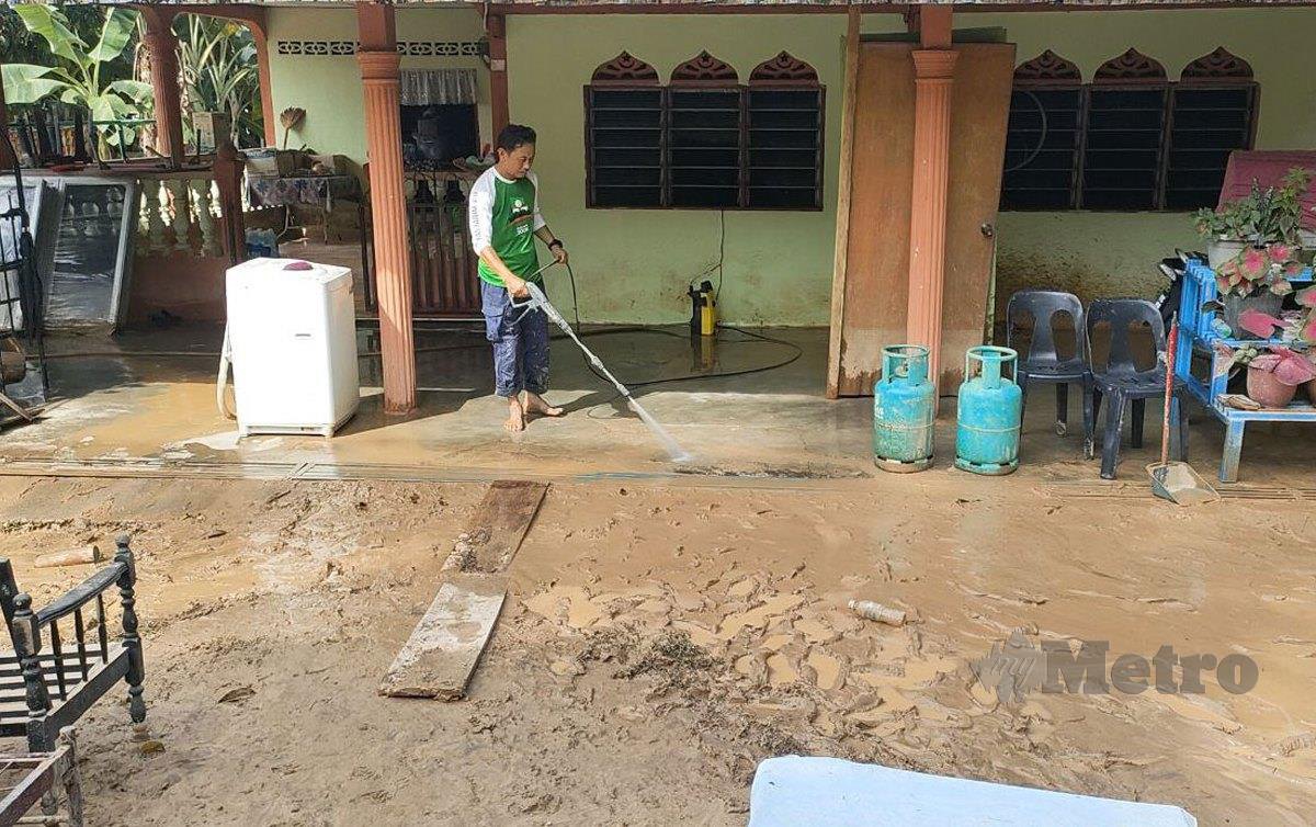 SOLIHIN Azman mencuci kawasan rumah kakak iparnya yang dipenuhi lumpur akibat fenomena kepala air di Kampung Iboi, Kupang. FOTO Zuliaty ZUlkiffli