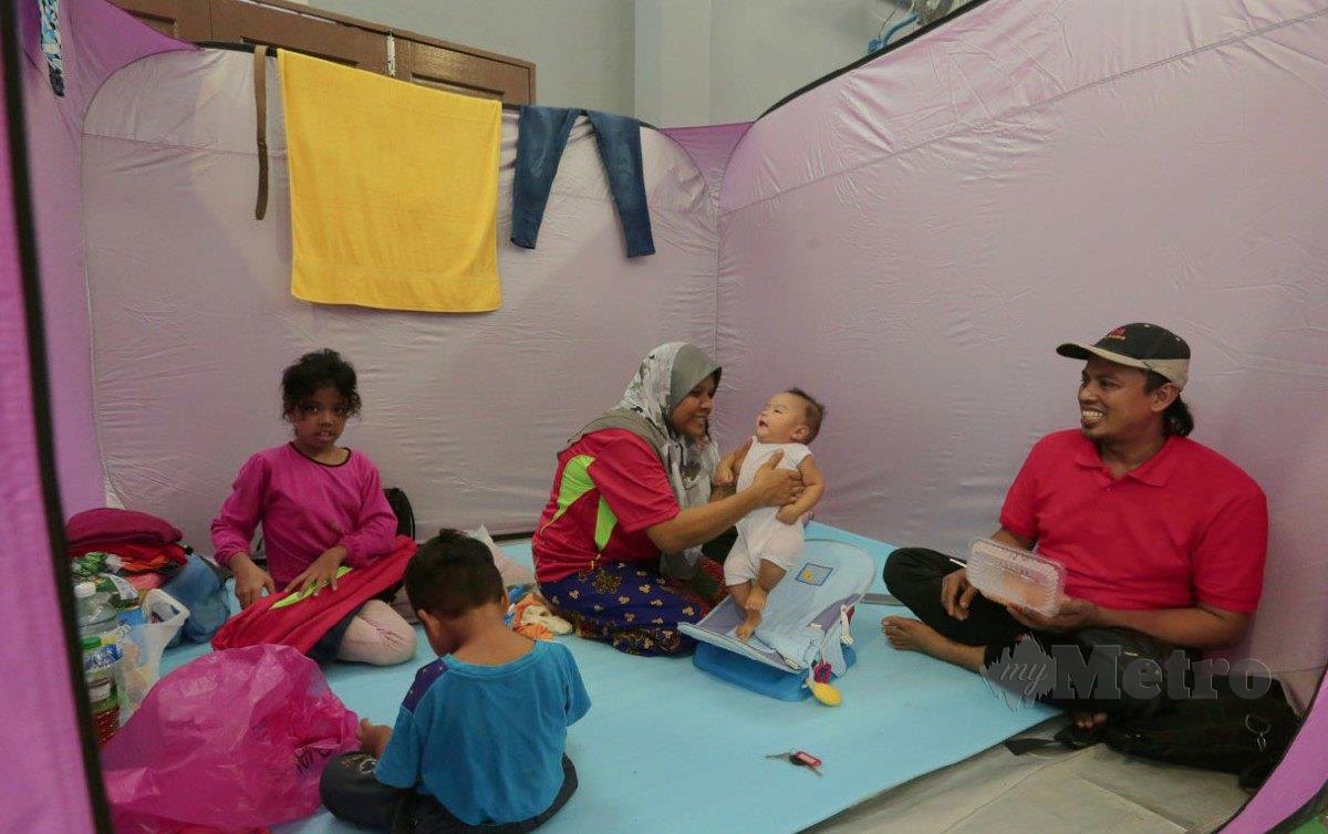 MANGSA (tengah) memegang anaknya yang berumur 4 bulan sambil diperhatikan suami dan anak-anaknya di Dewan Raya Kg Melayu Batu 10, Skudai, Johor. FOTO Nur Aisyah Mazalan