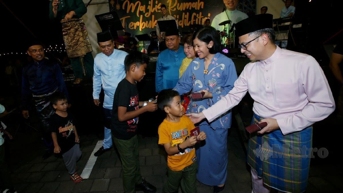 Menteri Komunikasi, Fahmi Fadzil bersama isteri, menyampaikan duit raya pada Majlis Rumah Terbuka Hari Raya Aidilfitri Parlimen Lembah Pantai di IWK Eco Park, Pantai Dalam. FOTO EIZAIRI SHAMSUDIN