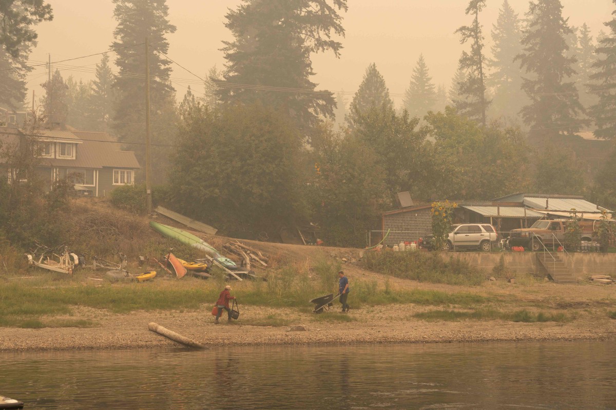 Penduduk Lee Creek, British Columbia membawa barang keperluan ke kediaman masing-masing. - FOTO AFP