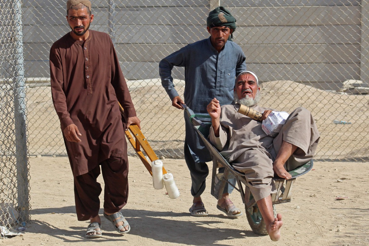 Seorang lelaki menolak warga emas yang tiba di sempadan Pakistan-Afghanistan di Chaman. - FOTO AFP