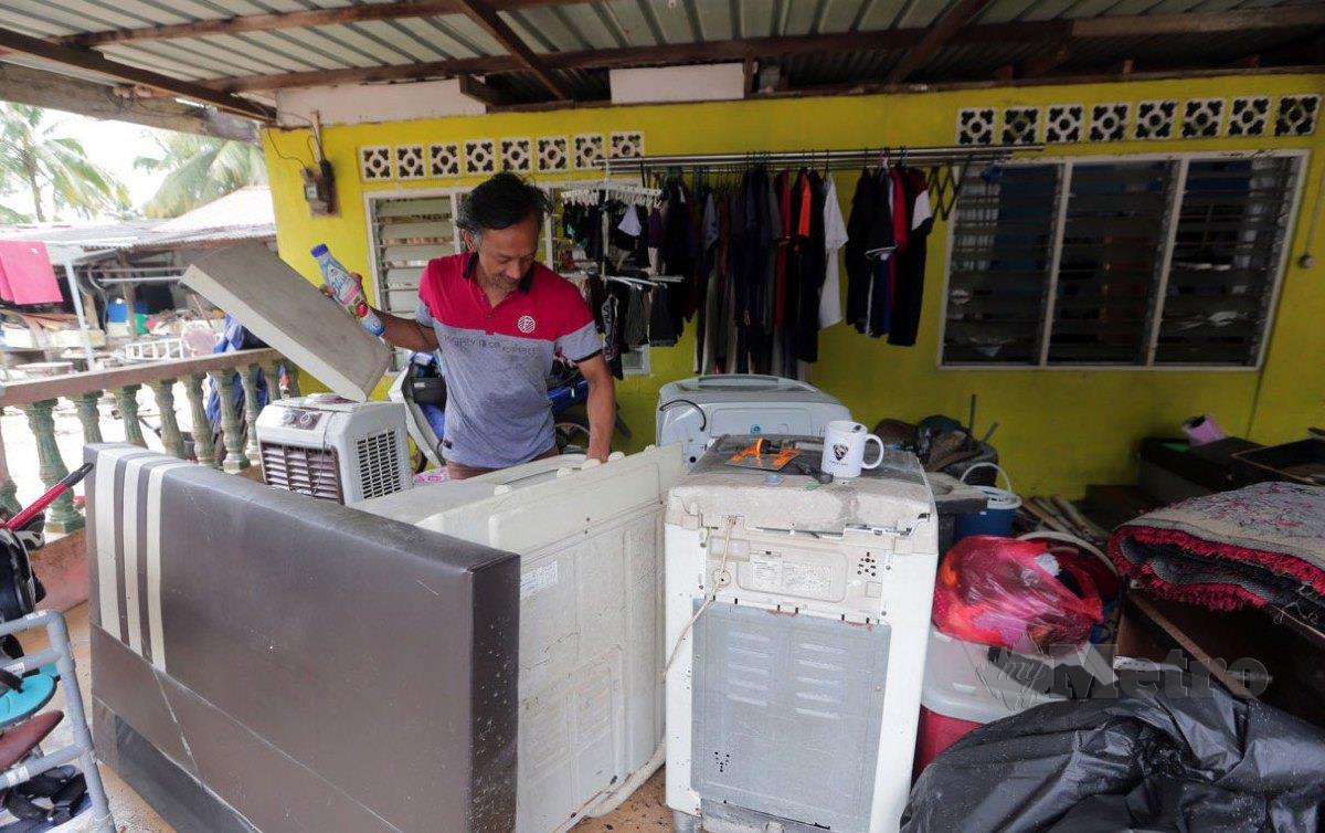 TUMIRAN memeriksa barangan elektrik yang dihantar kenalan dan pelanggan bagi dibaiki musnah ditenggelami banjir  di Kampung Baru, Gelang Patah, Johor. FOTO Nur Aisyah Mazalan