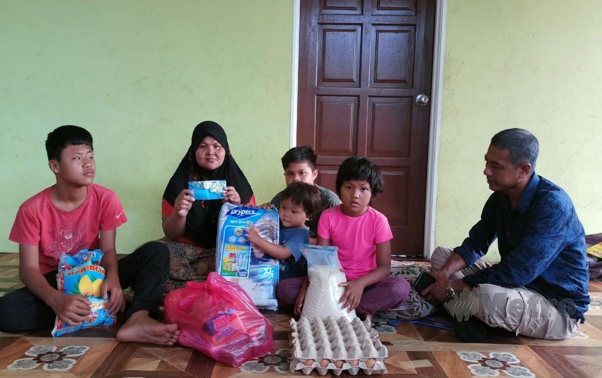 ZAHARI (kanan) hadir menyerahkan wang zakat dan sumbangan makanan kepada ibu tunggal, Siti Aminah Mat Zin, 41, di rumahnya di Taman Warisan Jaya, Kampung Laut. FOTO Siti Rohana Idris