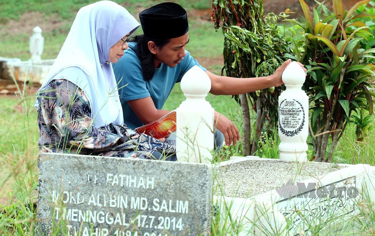 JUNAIDAH bersama Mohd Salman menziarahi pusara Allahyarham Mohd Ali Md Salim yang terkorban dalam tragedi nahas pesawat Malaysia Airlines MH17. FOTO Hairul Anuar Rahim