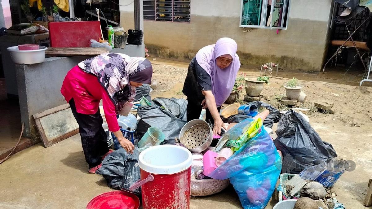 Penduduk Kampung Tawar membersihkan barangan mereka yang ditenggelami air akibat banjir kilat. FOTO ZULIATY ZULKIFFLI