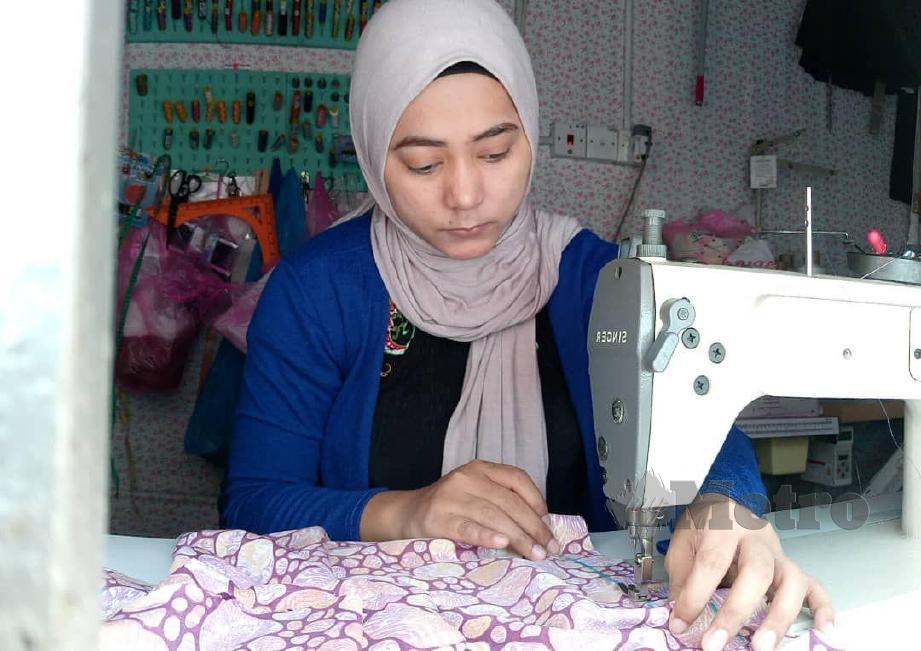 DAYANG  Nur’asmah giat menyiapkan tempahan baju raya milik pelanggan di Kota Kinabalu.  FOTO Yun Mikail