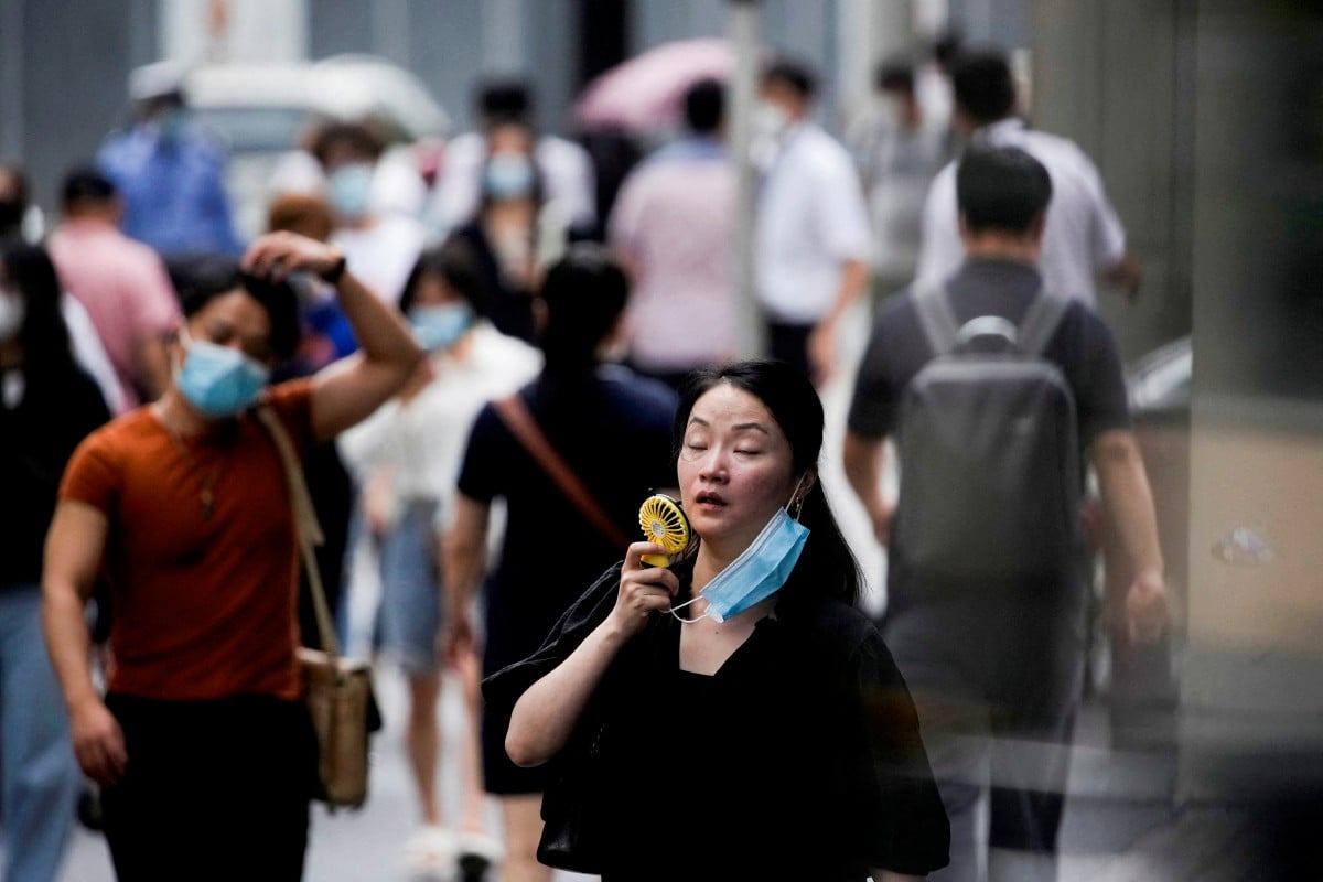 Seorang wanita membuka pelitup muka dan menggunakan kipas untuk menyejukkan wajahnya. - FOTO Reuters