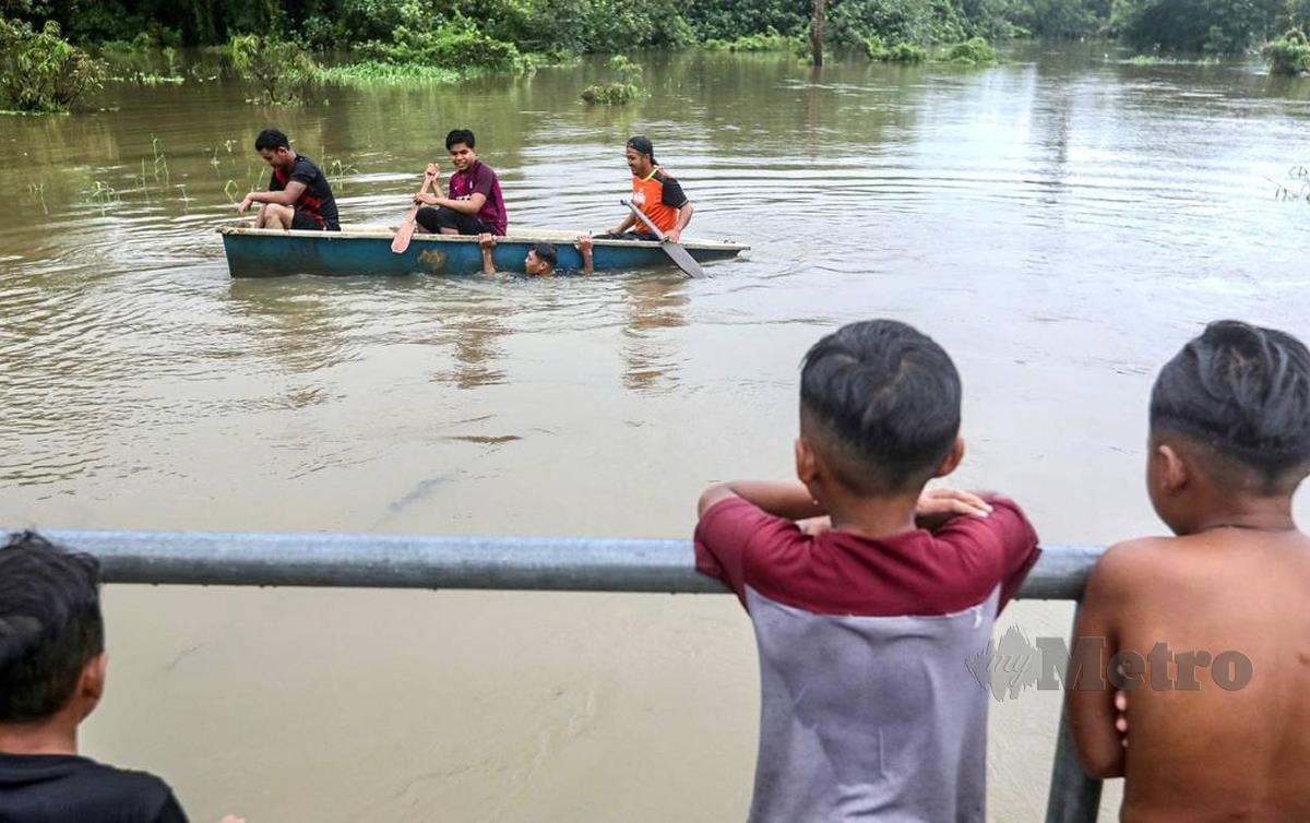 PENDUDUK mengayuh sampan selepas kawasan kediaman mereka dilanda banjir di Kampung Titian Baru. FOTO Ghazali Kori
