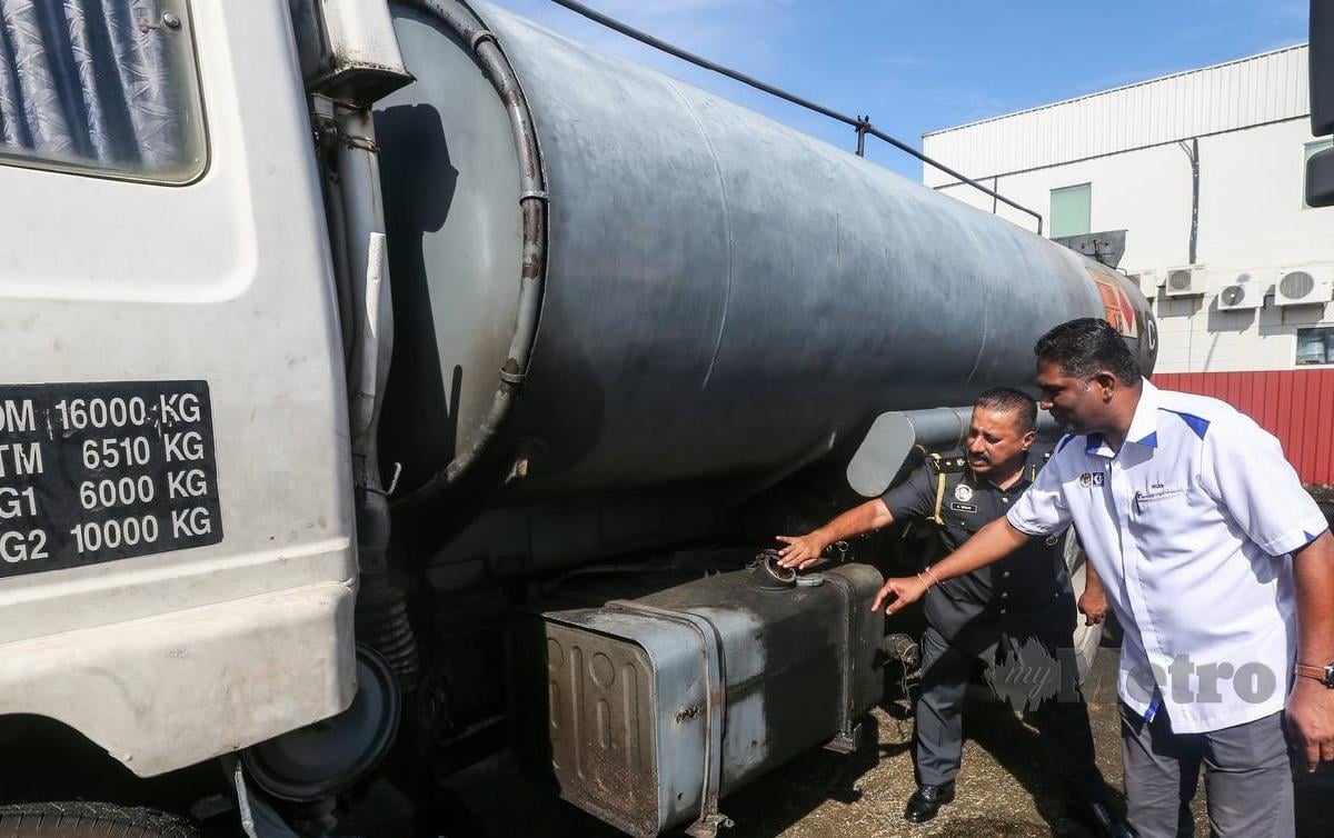 S Jegan (kanan) bersama A Mogan menunjukkan modus operandi pemindahan minyak diesel dari tangki minyak lori ke dalam tangki simpanan lori terbabit. FOTO Danial Saad