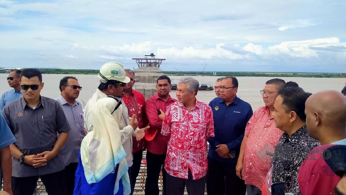AHMAD Zahid mendengar taklimat dari jurutera pembinaan Jambatan Bagan Datuk - Kampung Sejagop. FOTO MUHAMAD LOKMAN KHAIRI.