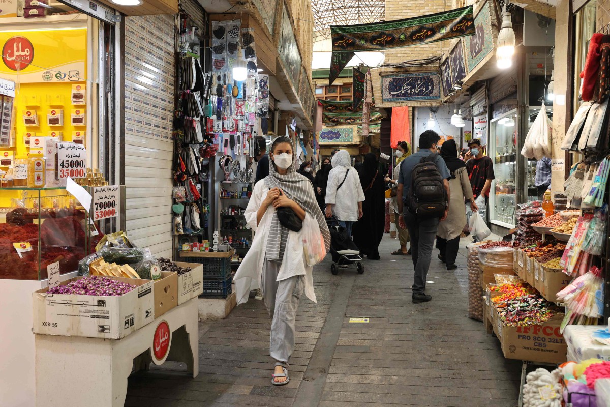 Seorang wanita mengenakan pelitup muka ketika membeli barangan di Tajrish Bazaar, Tehran. - FOTO AFP