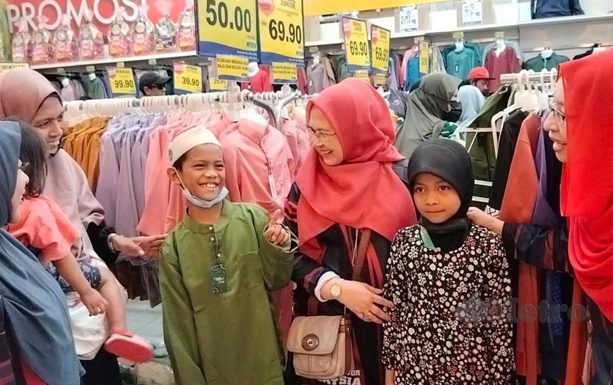 ZURAINI Kamal (kanan) memilih baju raya untuk anak-anak kepada Nor Aza Hamzah (dua dari kiri) ketika membeli belah di pasaraya Mydin. FOTO Zuliaty Zulkiffli