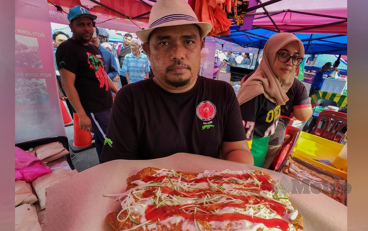 MOHD Tarmimi Mohd Sharap, 36, (kiri) menjual roti john dengan harga RM1 di Bazar Ramadan Bandar Baru Nilai. FOTO Azrul Edham