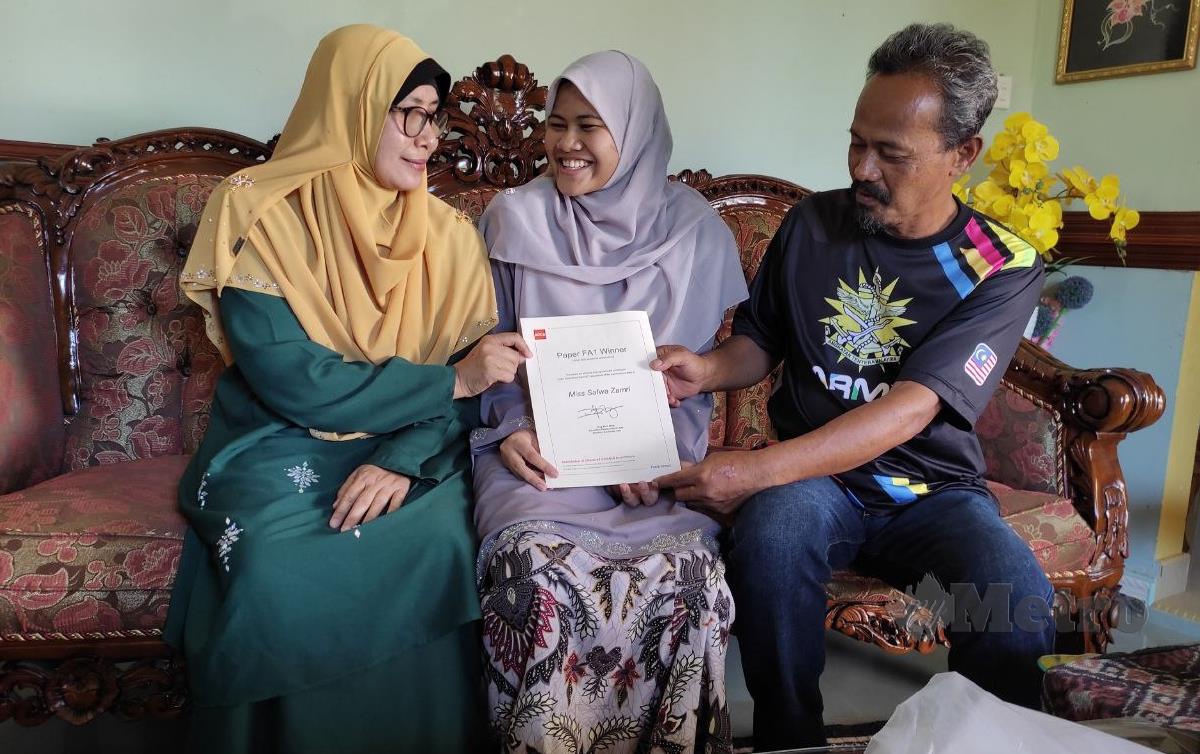PELAJAR cemerlang Safwa bersama ibu bapanya menunjukkan sijil kecemerlangannya di kediaman keluarganya. FOTO Nurul Fatihah Sulaini