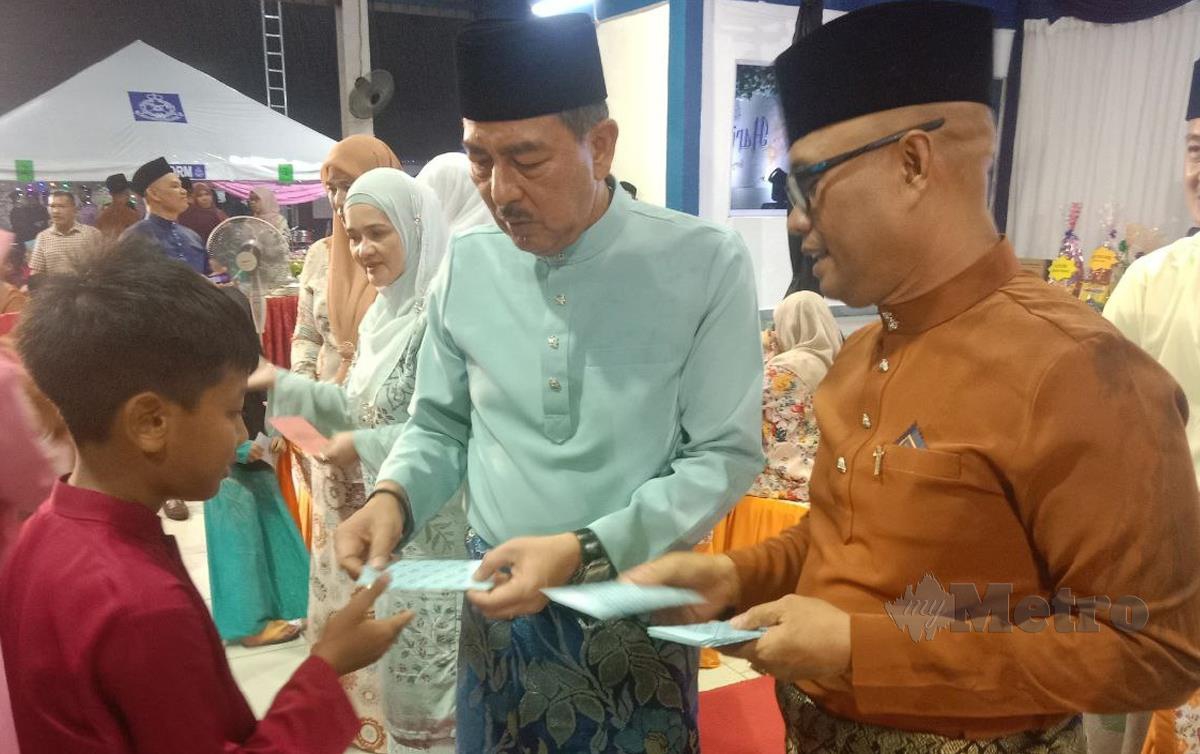 DATUK Muhamad Zaki Harun (tengah) menyampaikan duit raya kepada anak-anak polis sempena sambutan Aidilfitri peringkat IPD Pasir Puteh. FOTO Nor Amalina Alias