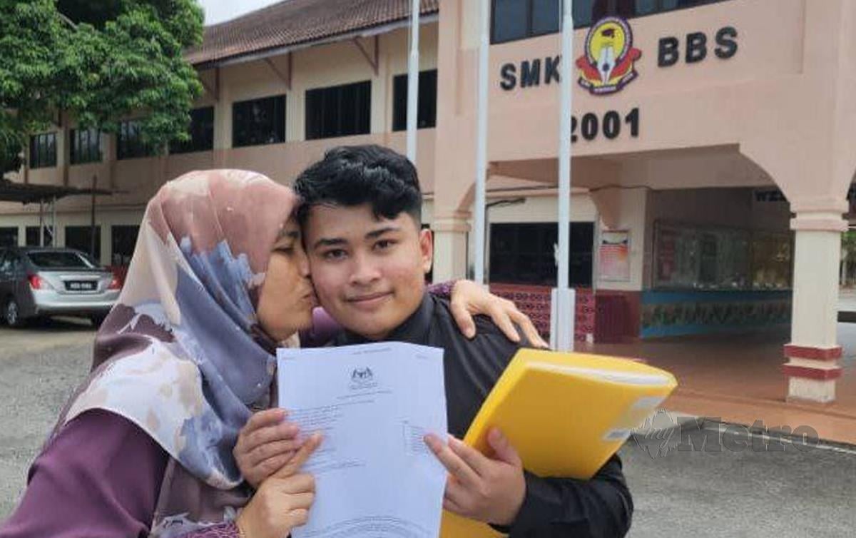 WAN Muhammad yang memperoleh keputusan cemerlang dalam SPM bersama ibunya, Shahrul Afizah Ahmad di hadapan sekolahnya. FOTO Zuliaty Zulkiffli