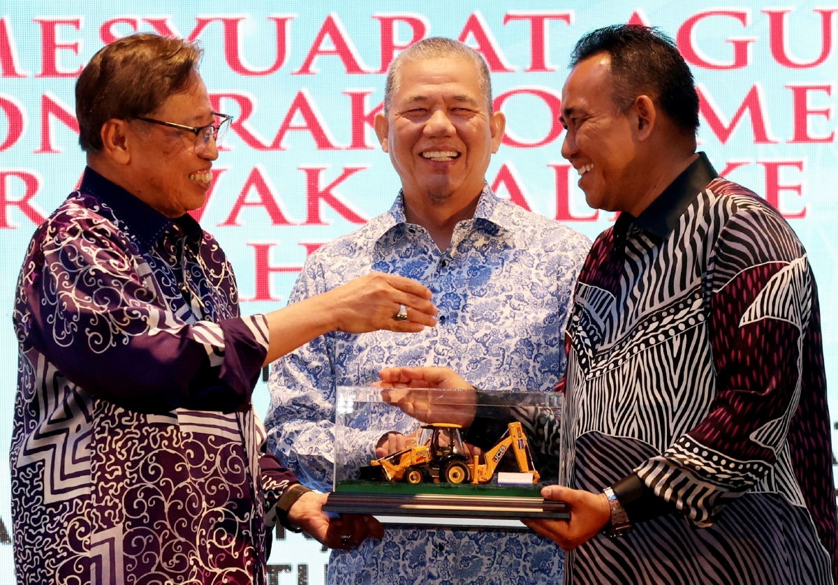 JOHARI Tun Openg menerima model jentolak daripada Yang Dipertua PKMM Sarawak Datuk Ismail Suut (kanan) sebagai simbolik pemberian tiga jentera tersebut. FOTO Bernama