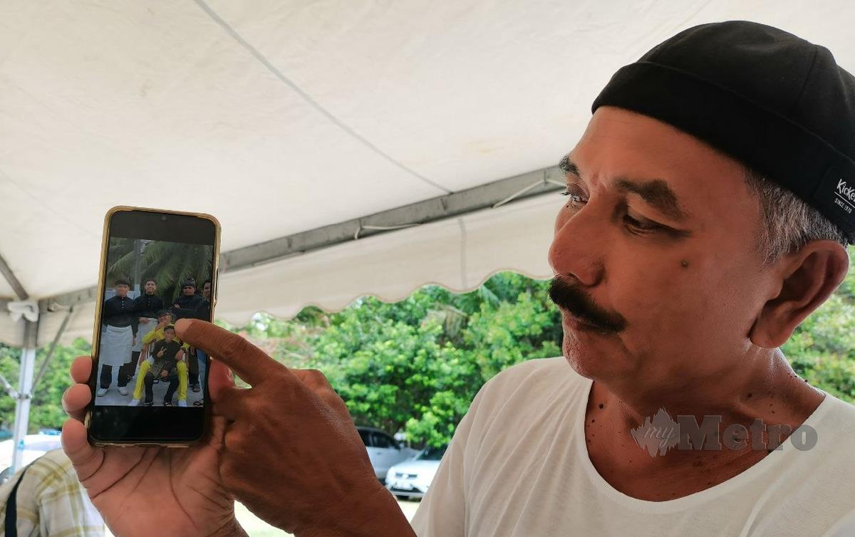 Masdi bapa kepada Laskar Udara I Mohd Iqmal menunjukkan foto Allahyarham bersama keluarga pada telefon bimbitnya. FOTO Ahmad Hasbi