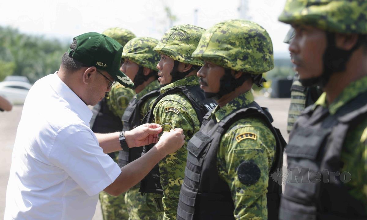 SAIFUDDIN Nasution Ismail (kiri) melekatkan patches kawalan sempadan RELA kepada anggota RELA. FOTO Syaharim Abidin