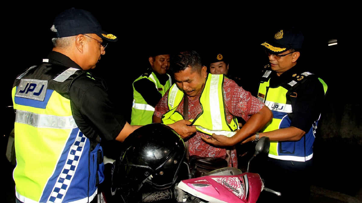 Datuk Lokman Jamaan memakaikan vest keselamatan kepada penunggang ketika  Op Khas Motosikal bagi negeri Perak sempena Op Bersepadu HRA 2023 di Perak. FOTO BERNAMA