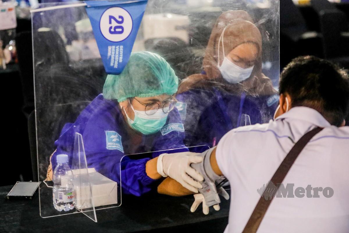 Seorang lelaki menerima suntikan vaksin Covid-19 di Medan, Indonesia. - FOTO EPA