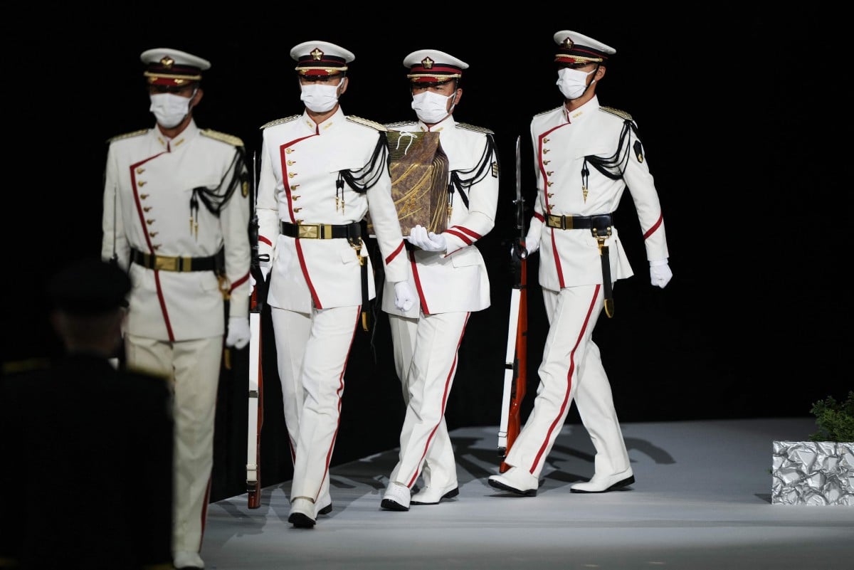 Pegawai kehormat membawa bekas mengandungi abu mayat Abe pada majlis penghormatan negara di Tokyo. - FOTO AFP