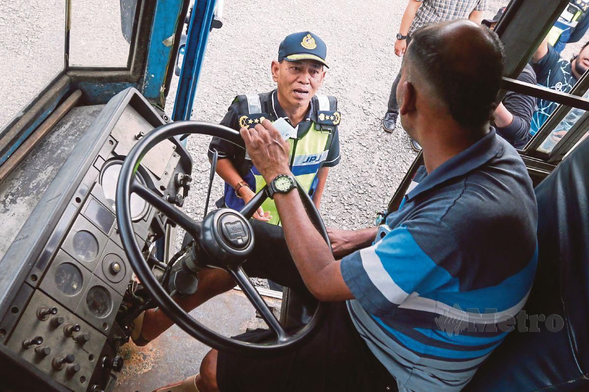 ADENAN (kiri) memeriksa pemandu bas kilang membawa penumpang tanpa lesen ketika ditahan. FOTO Danial Saad