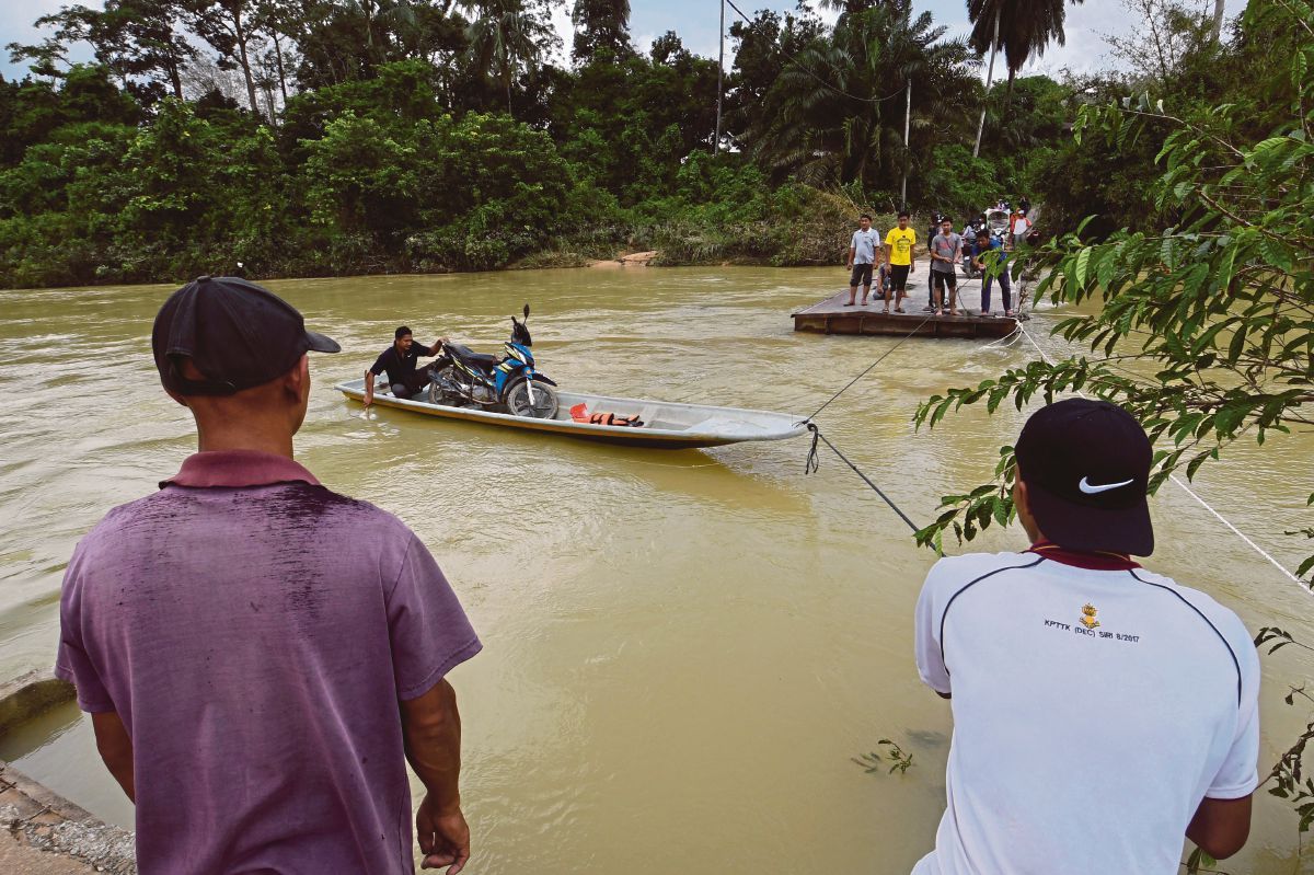 PENDUDUK kampung menggunakan bot untuk merentasi sungai selepas jambatan Kampung Pasir Jering runtuh. FOTO Bernama
