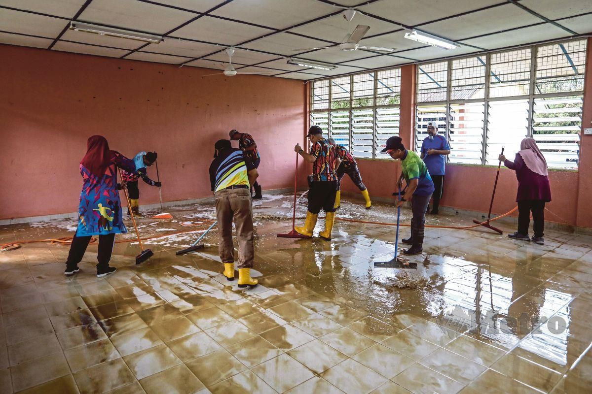 PASUKAN sukarelawan KPM membersihkan ruang kelas yang terjejas banjir di Sekolah Kebangsaan Sungai Las, Setiu. FOTO Ghazali Kori