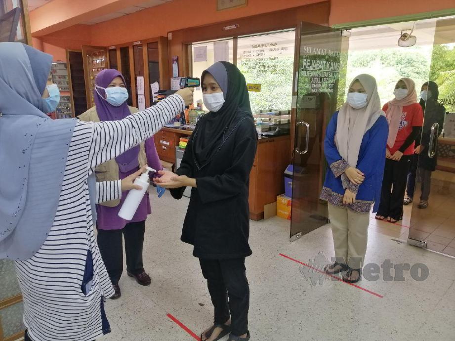 ZALINA Ismail (dua kiri) memerhatikan proses saringan ke atas pelajar yang tiba di Politeknik Sultan Salahuddin Abdul Aziz Shah (PSA). FOTO Ruwaida Md Zain