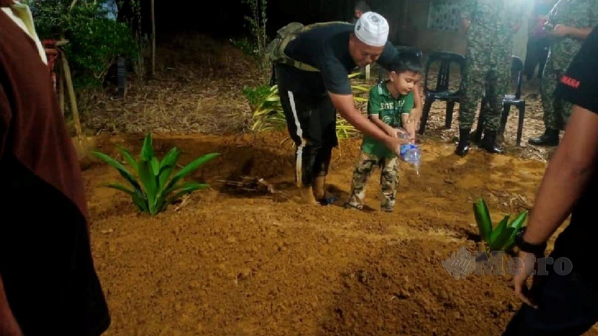 Sudirman menyirami kubur anaknya, Aiman Syafiq yang selamat dikebumikan di Tanah Perkuburan Islam Masjid Mukim Badak, Melawi, Bachok. FOTO Nor Amalina Alias