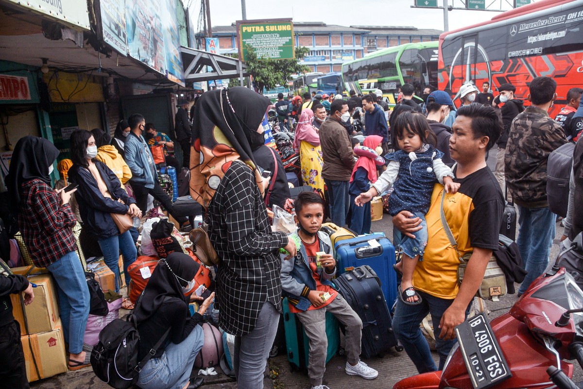 Ratusan penumpang menanti giliran menaiki bas masing-masing di terminal di Bekasi, menuju kampung halaman sempena sambutan Aidilfitri. - FOTO AFP