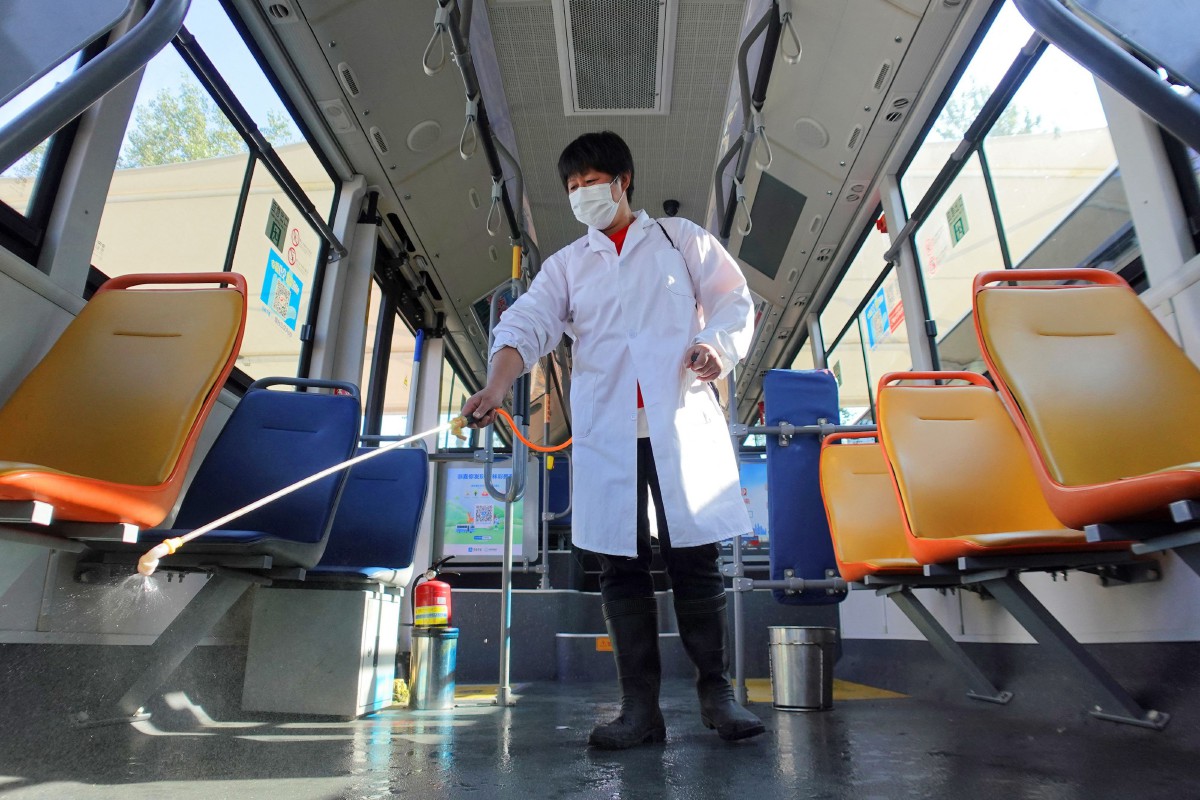 Kakitangan menyembur cecair disinfektan dalam bas bagi mengekang penularan Covid-19 di Yantai, wilayah Shandong, China. - FOTO AFP