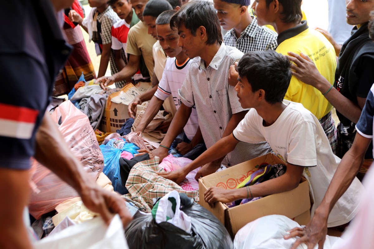 Sebahagian pendatang Rohingya memilih pakaian terpakai yang didermakan penduduk tempatan di Pidie, Aceh. - FOTO EPA