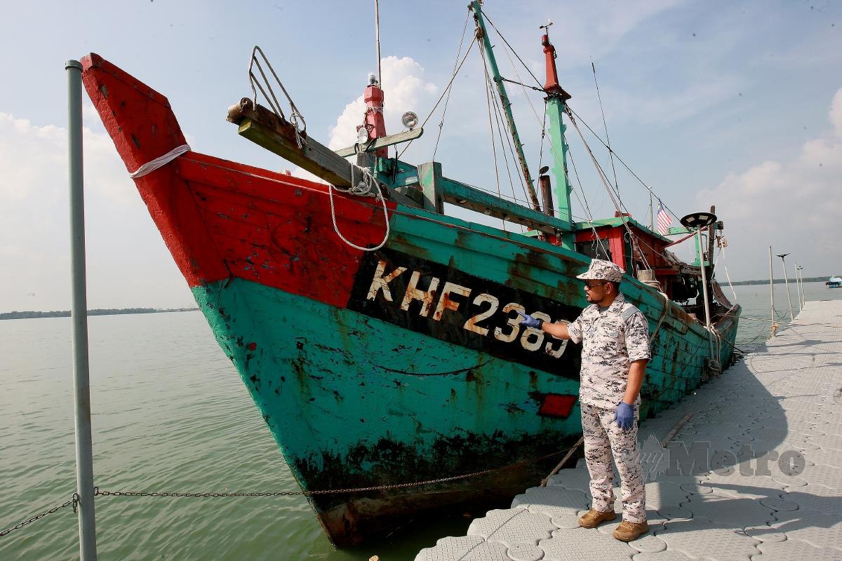 MUHAIMIN Muhammad Salleh menunjukkan sebuah bot nelayan dirampas yang membawa 38 bungkusan teh cina berisi dadah jenis syabu. FOTO Faiz Anuar