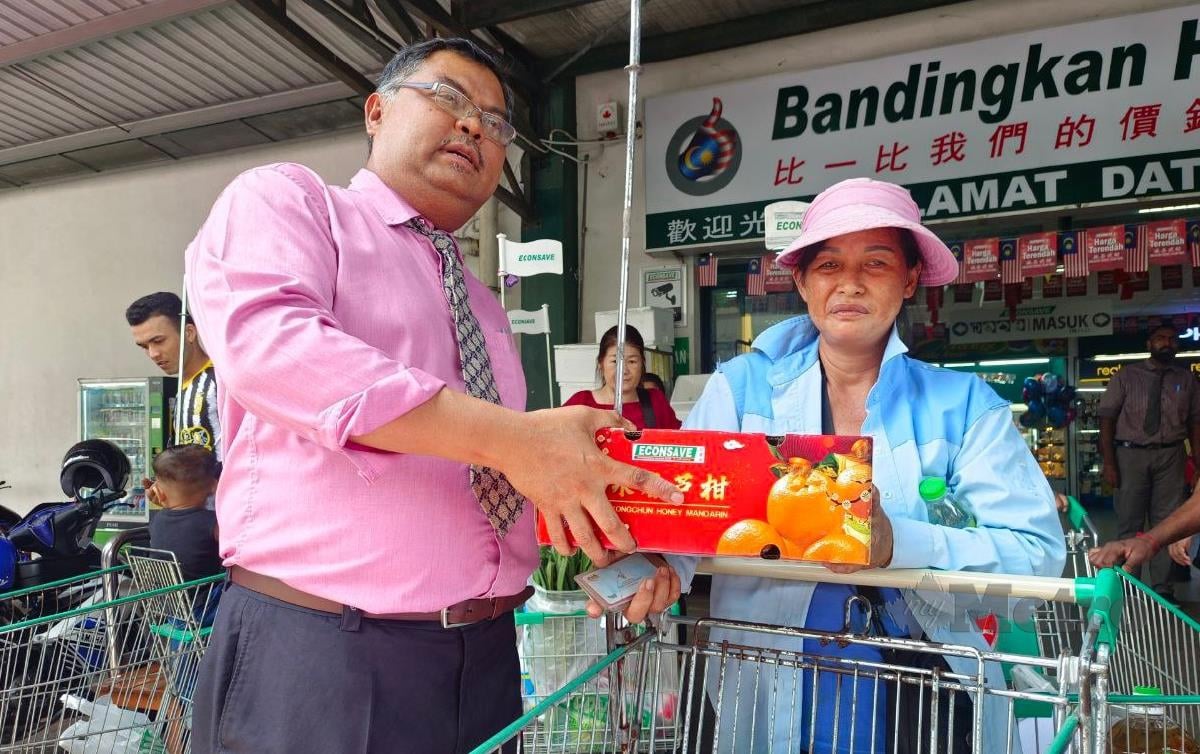 KHOO Chin Hwa, menerima kotak limau disampaikan oleh Pengurus Besar Pasaraya Econsave Cash and Carry Mas Imran Adam. FOTO Mary Victoria Mass