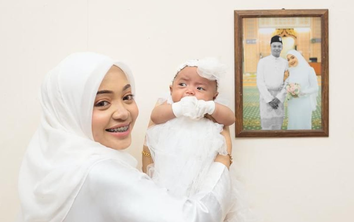 AIMI bersama anak tunggalnya Elnur Aileen Feliya merakam kenangan bersama gambar suami, Muhammad Firdaus pada majlis akikah anaknya.