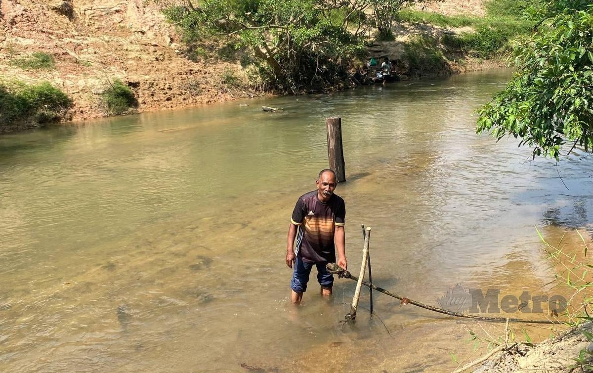 MUKHTAR menunjukkan saluran paip yang dipasang untuk menyalurkan air dari Sungai Rek ke rumahnya. FOTO Hazira Ahmad Zaidi