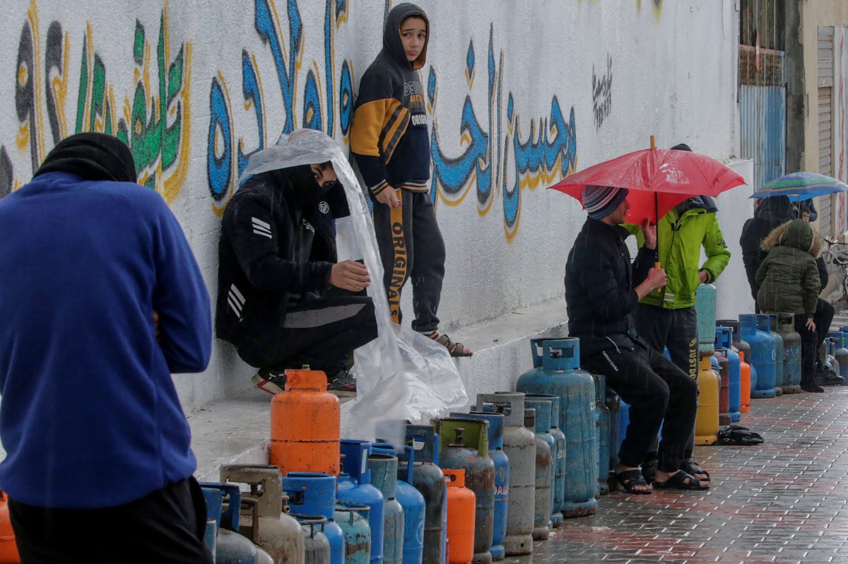 Warga Palestin menunggu giliran membuat isian semula gas memasak dalam cuaca sejuk di Semenanjung Gaza. Kebanyakan rakyat Palestin menggunakan bateri atau lilin untuk menerangi kediaman. - FOTO EPA
