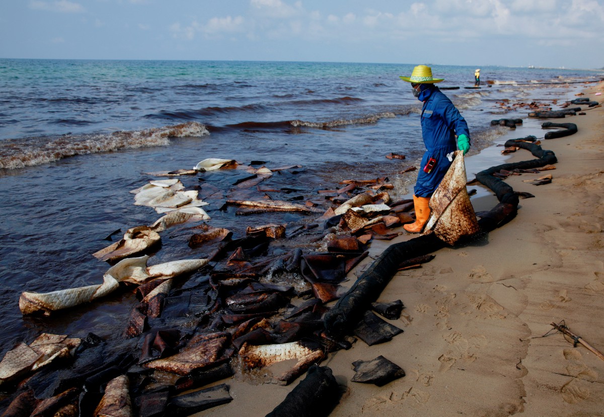 Kakitangan membersihkan sisa minyak di tepi pantai di Mae Ramphueng wilayah Rayong, Thailand. - FOTO Reuters